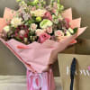 Pink and cream mixed bouquet wrapped in pink paper with a ribbon