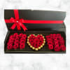Black gift box with red roses and chocolates arranged in heart shapes