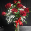 Deep, velvety red roses arranged upright in a clear glass vase create