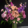 A lush, garden-style bouquet of mixed pink, purple, peach and white flowers