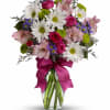 Mixed bouquet of daisies, roses, and alstroemeria in a glass vase with a magenta ribbon