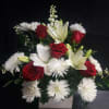 Deep red roses set against crisp white lilies and daisy-like blooms create