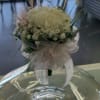 White floral arrangement in a clear glass vase with a sheer ribbon bow