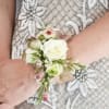 Wrist corsage of white roses and small pink flowers on a beaded dress.