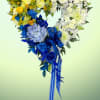 Heart-shaped bouquet of yellow, white, and blue flowers with a ribbon