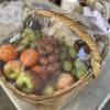 Gift basket of apples, oranges, and grapes wrapped in cellophane with a decorative bow