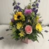 Mixed bouquet with pink rose, sunflower, purple blooms, and yellow daisies in a pink box