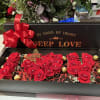 A low black rectangular gift box filled with lush red roses creates