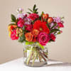 Mixed bouquet of roses, gerbera daisies, and carnations in a clear glass vase