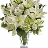 White lilies and mixed white flowers in a clear glass vase
