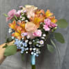 Soft pink roses, bright orange alstroemeria, pink mini carnations and blue baby