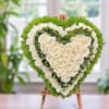 Heart-shaped floral arrangement of white roses and green hydrangeas on an easel