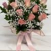 Pink roses and white baby's breath arranged in a pink box with ribbon.