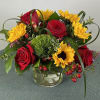 Bouquet of red roses and yellow sunflowers in a clear glass vase