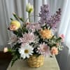 Basket arrangement of pastel flowers with daisies and lilac blooms