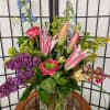 Mixed bouquet with pink lilies, purple hydrangea, and blue delphinium in a glass vase