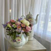 Pastel flower arrangement in a floral teapot vase on a table