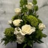 White roses and green blooms arranged in a black square vase