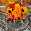 Bouquet of sunflowers, marigolds, and roses with autumn leaves