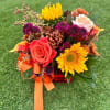 Colorful bouquet with roses, sunflowers, and purple blooms tied with orange ribbon