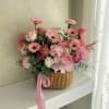 A lush cluster of pink gerbera daisies, roses, and carnations arranged low