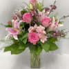 Pink roses and lilies arranged in a clear glass vase