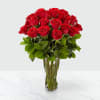 Tall clear glass vase filled with a large bouquet of long-stemmed red roses.