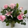Pink roses and pink lilies arranged in a clear glass vase