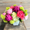 Pink and magenta flowers arranged in a white vase