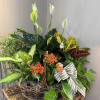 Basket planter with white peace lilies, orange blooms, and assorted foliage