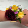 A lush burgundy ranunculus takes center stage in this Velvet Meadow Corsage