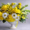 Yellow and white floral arrangement in a white pedestal vase