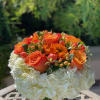 Orange roses and white hydrangeas in a clear glass vase