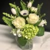 White and pale green floral arrangement in a glass vase