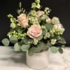 Blush roses and white filler flowers in a white vase