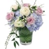 Bouquet of pink and white roses with blue hydrangeas in a glass vase
