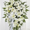 White funeral spray with lilies, roses, and chrysanthemums on a stand