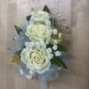 This classic wrist corsage features soft white roses, delicate baby&rsquo;s breath, and