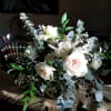A romantic garden-style centerpiece featuring soft white and blush blooms accented with