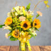 Bright sunflowers and white lilies dance together in this cheerful flower arrangement