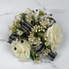 Cream-white roses contrasted with black and silver shimmering ribbon make this wrist