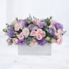 Low arrangement of pink roses and lavender lisianthus in a white rectangular wooden box