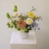 Pastel arrangement of daffodils, roses, chrysanthemum and mixed flowers in a white ribbed vase