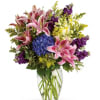 Pink lilies and purple flowers in a clear glass vase