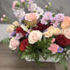 A lush bouquet of mixed roses and soft accents, this pink basket