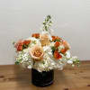 Peach roses and white flowers arranged in a black vase