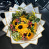Bouquet of yellow roses and sunflowers wrapped in white paper