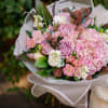 Pink and lavender bouquet with hydrangea and roses wrapped in white paper