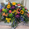 This colorful casket spray includes a variety of wildflowers