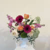 Mixed bouquet in a white pedestal vase with pink, orange, and white blooms